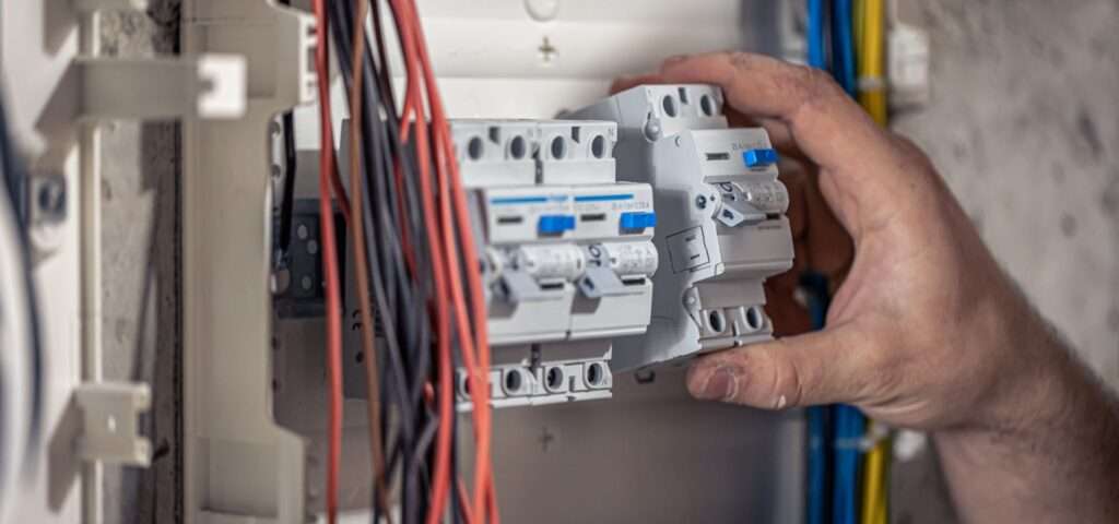 electrician installing ceiling fan in home
